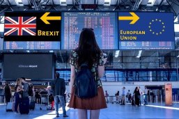 Eine junge Frau steht an einem Flughafen. An den Anzeigetafeln im Terminal werden Brexit und Europäische Union angezeigt. Sie steht vor der Entscheidung