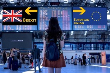 Eine junge Frau steht an einem Flughafen. An den Anzeigetafeln im Terminal werden Brexit und Europäische Union angezeigt. Sie steht vor der Entscheidung