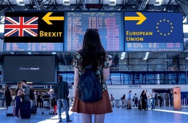 Symbolbild zum Brexit Eine junge Frau steht an einem Flughafen. An den Anzeigetafeln im Terminal werden Brexit und Europäische Union angezeigt. Sie steht vor der Entscheidung