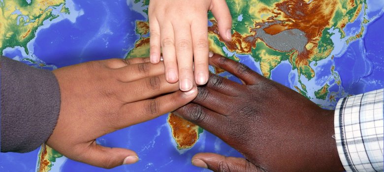 Kinderhände liegen auf einer Weltkarte und symbolisieren Einigkeit