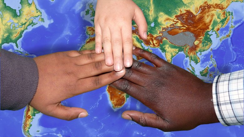 Kinderhände liegen auf einer Weltkarte und symbolisieren Einigkeit