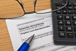 Gewerbeanmeldung ausfüllen Symbolbild: Antrag auf eine Gewerbeanmeldung. Daneben liegt eine Brille und ein Taschenrechner