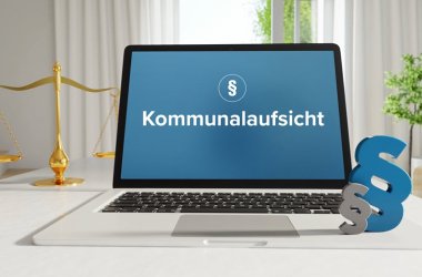 Kommunalaufsicht – Recht, Gesetz, Internet. Laptop im Büro mit Begriff auf dem Monitor. Paragraf und Waage.