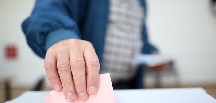 Ein Mann gibt im Wahllokal seinen Stimmzettel ab. 