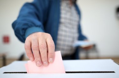 Ein Mann gibt im Wahllokal seinen Stimmzettel ab. 