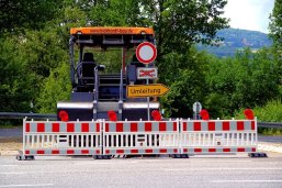 Straße Bauarbeiten eine gesperrte Straße. Es finden Bauarbeiten statt. Eine Asphaltiermaschine ist zu sehen.