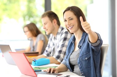 Proud student posing with thumbs up at classroom