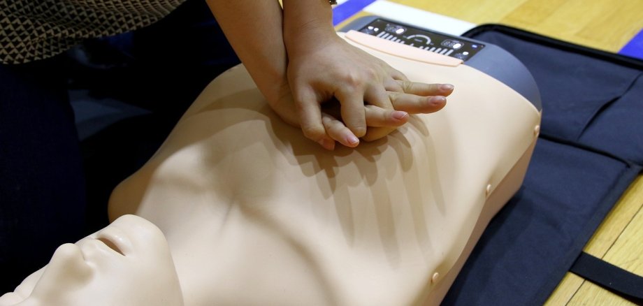 Eine Person führt an einem Dummy die Herzdruck-Massage vor.