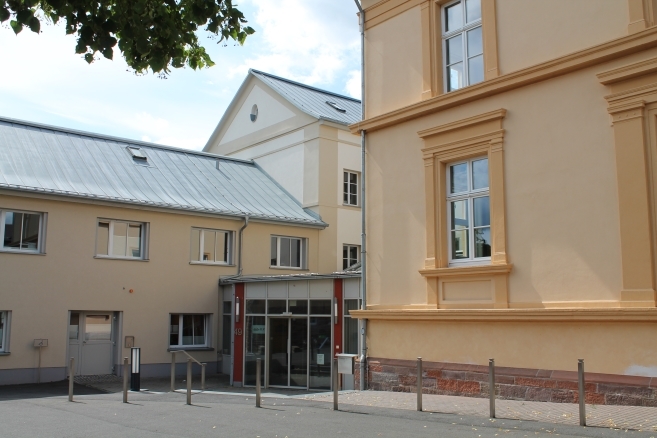 auf dem Bild ist der Eingangsbereich der KVA mit ocker-farbenen Hausfassaden zu sehen.