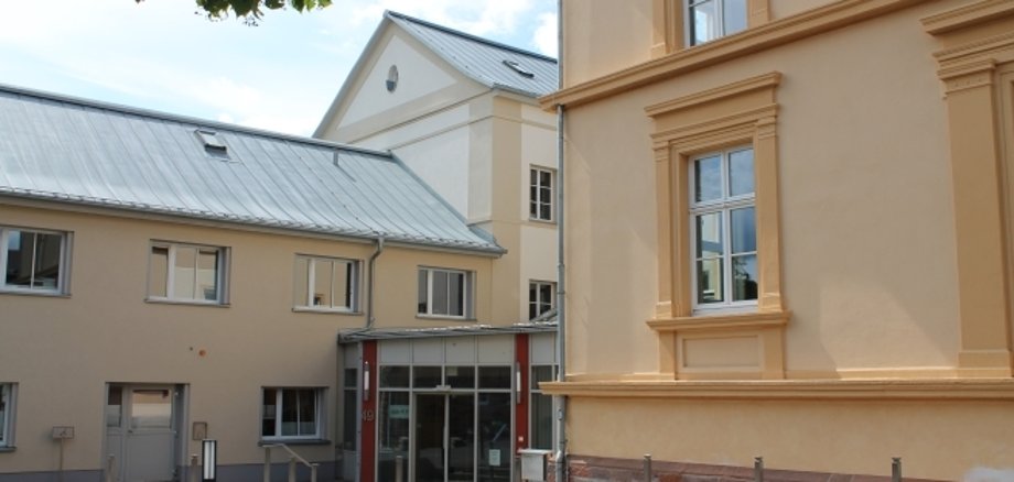 auf dem Bild ist der Eingangsbereich der KVA mit ocker-farbenen Hausfassaden zu sehen.