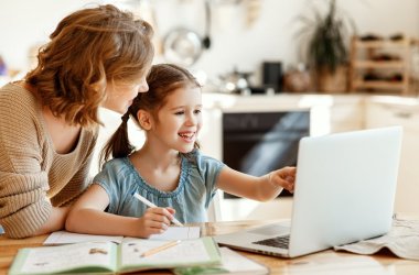 Happy girl with mother studying online at home