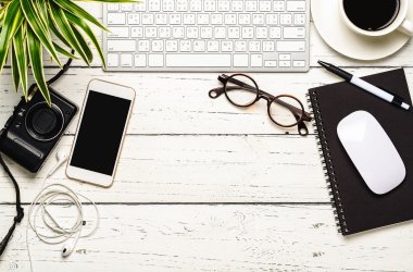 Workspace desk with keyboard, smart phone, camera, earphone, eye