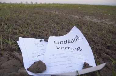 Auf Acker liegt symbolisch ein Kaufvertrag Auf Acker liegt symbolisch ein Kaufvertrag