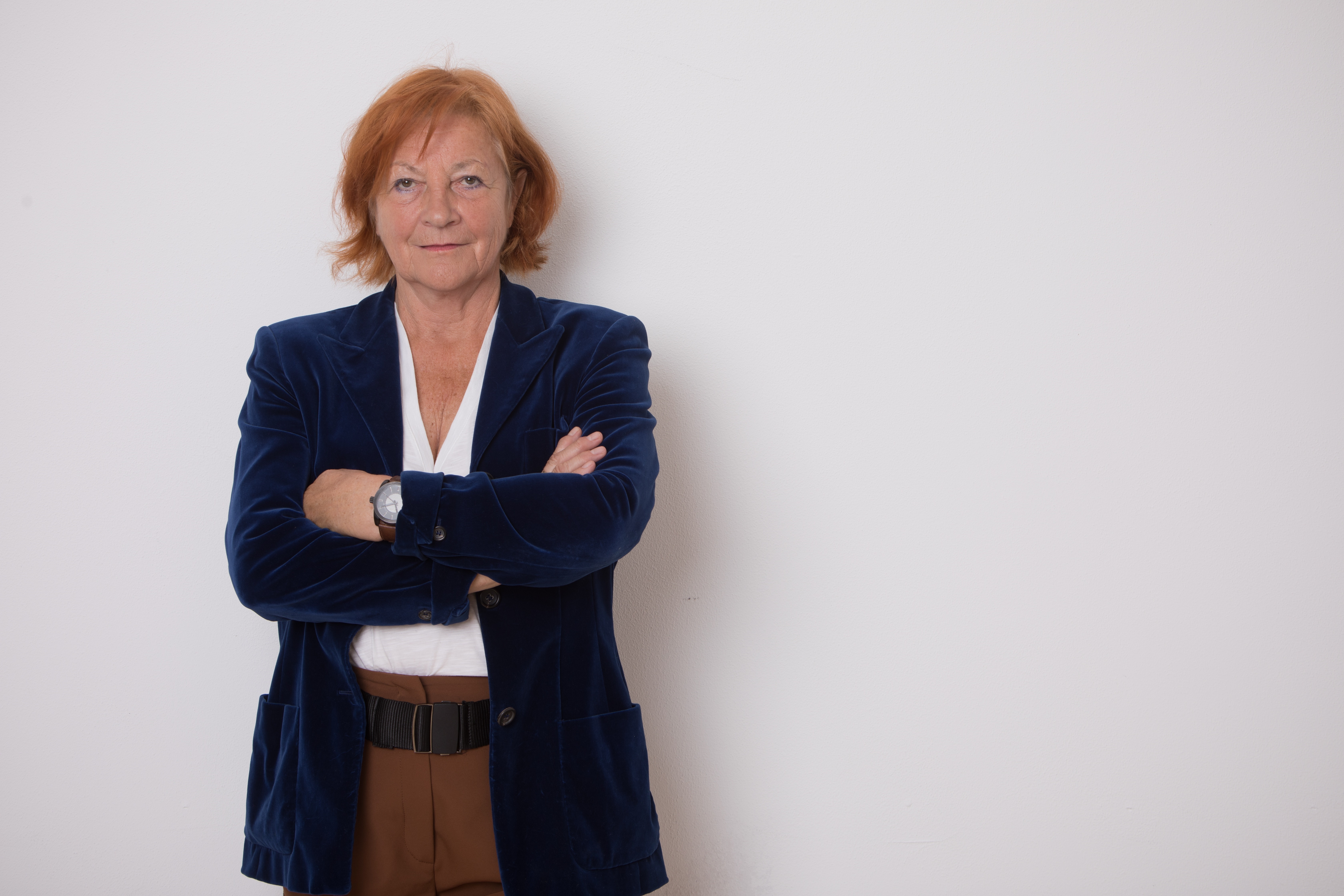 Elisabeth Hillebrand schaut mit verschränkten Armen in die Kamera. Sie trägt einen dunkelblauen Blazer.