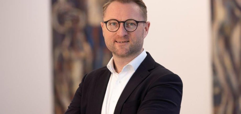 Porträtfoto  von Landrat Dr. Jens Mischak. Er schaut mit verschränkten Armen in die Kamera.