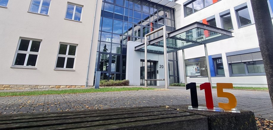 Eingangsbereich der Kreisverwaltung. im Vordergrund ist eine Sitzbank zu sehen. 