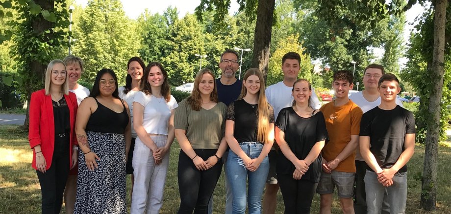 Alexander Tönnies (zweite Reihe Mitte) begrüßt die Azubis aus dem Vogelsbergkreis im Landkreis Oberhavel. Sie haben sich unter einem Baum zum Gruppenbild aufgestellt. 