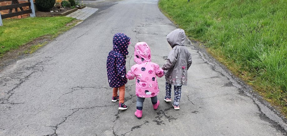Drei Kinder gehen auf einer Straße sapzieren