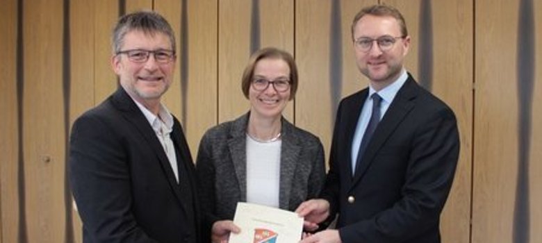 Andreas Fey, Bürgermeister der Stadt Kirtorf, erhält den Förderbescheid von Angelika Boese und Erstem Kreisbeigeordnetem Dr. Jens Mischak.