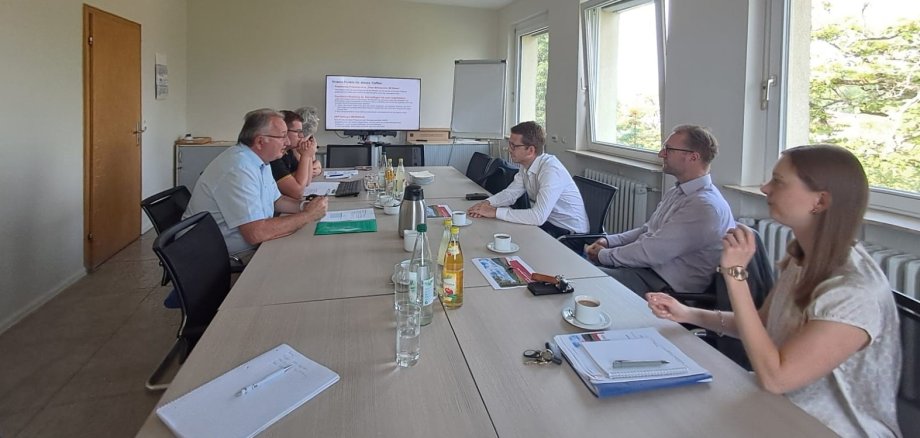 Landrat Dr. Jens Mischak und Staatssekretär Michael Ruhl im Gespräch mit den Fachleuten des Amtes für Wirtschaft und den ländlichen Raum in Lauterbach. Sie sitzen gemeinsam an einem langen Tisch.