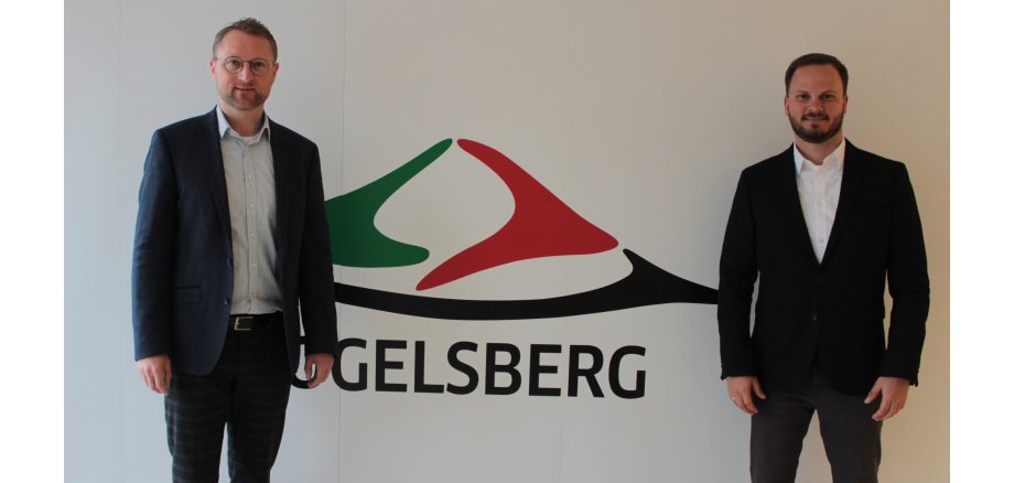 Dr. Jens Mischak und Dominic Günther stehen vor einer weißen Wand. Dominic Günther ist der neue Bewegungskoordinator im Vogelsbergkreis. 