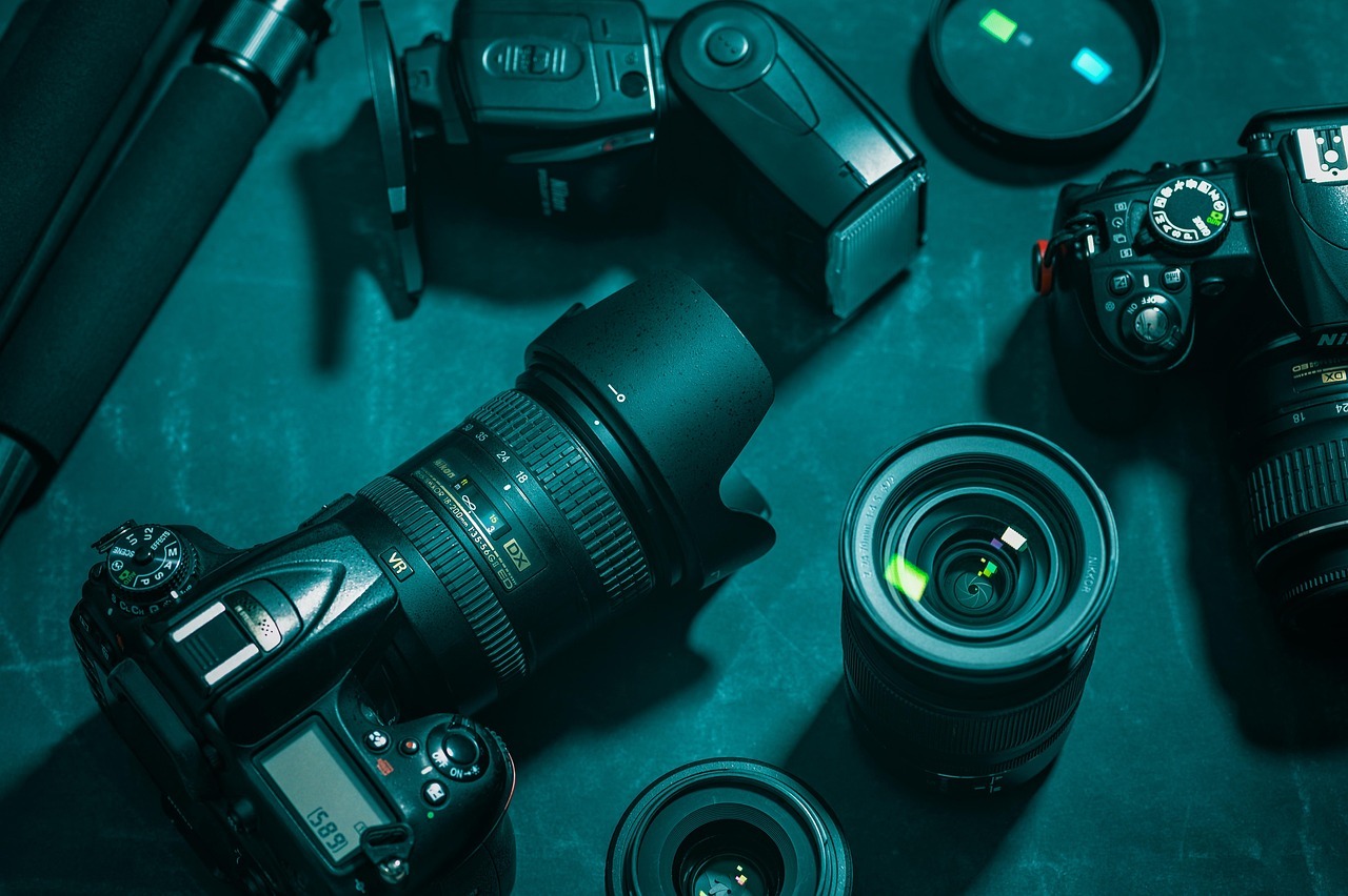 Fotozubehör ist auf einem Tisch ausgebreitet. Darunter ein Fotoapparat und verschiedene Objektive.