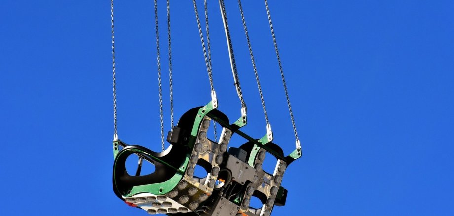 Symbolbild von zwei Sitzen eines Kettenkarussells. im Hintergrund ist blauer Himmel zu sehen.