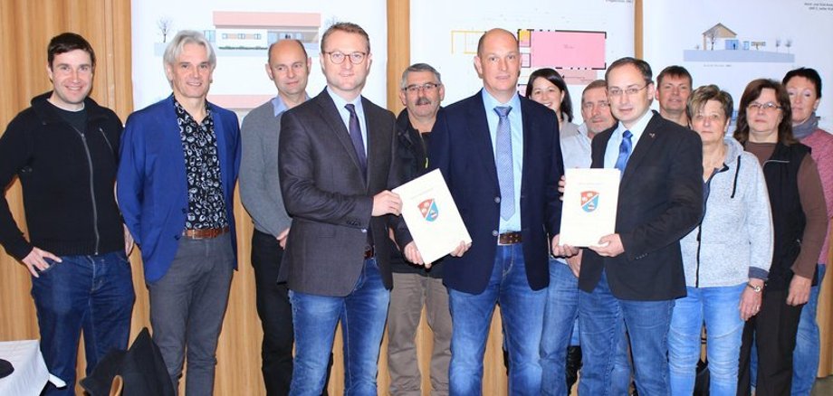 Gruppenbild mit Förderbescheid. Wirtschaftsdezernent Dr. Jens Mischak (Vierter von links) überreicht Bescheide in Höhe von rund 640.000 Euro für das neue „Dörfer-Gemeinschaftshaus“ Herchenhain/Hartmannshain – Freude bei der Dorfgemeinschaft, bei Bürgermeister Sebastian Stang (vorne rechts) und Ortsvorsteher Marko Straßberger (links neben dem Bürgermeister). 