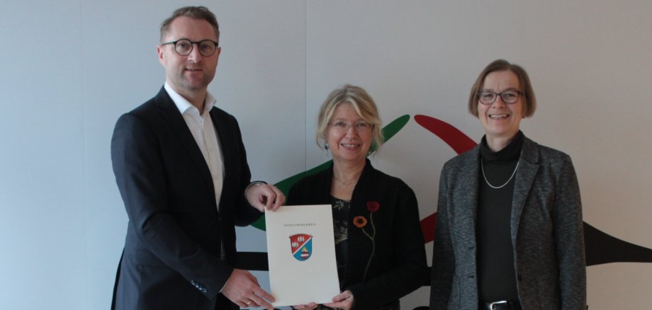 Erster Kreisbeigeordneter Dr. Jens Mischak und Angelika Boese, die Leiterin des Sachgebietes Dorf- und Regionalentwicklung, überreichen Schottens Bürgermeisterin Susanne Schaab den Zuwendungsbescheid in Höhe von 100.000 Euro. 