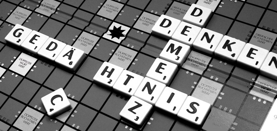 Auf einem Scrabble-Spielbrett sind die Worte Denken, Demenz und Gedächtnis mit Spielsteinen gelegt. 