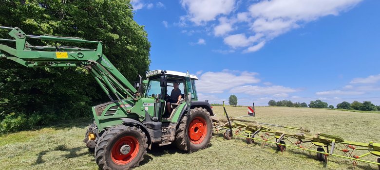 Hartmut Eifert auf seinem Traktor. Er ist mit dem Wender auf seiner Wiese unterwegs und macht Heu.