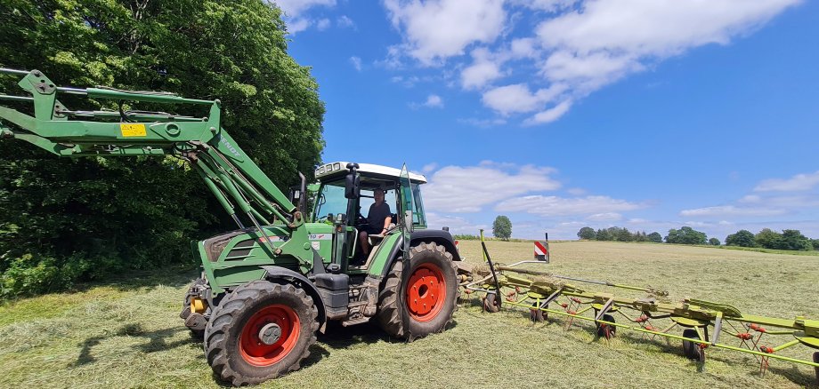 Hartmut Eifert auf seinem Traktor. Er ist mit dem Wender auf seiner Wiese unterwegs und macht Heu.