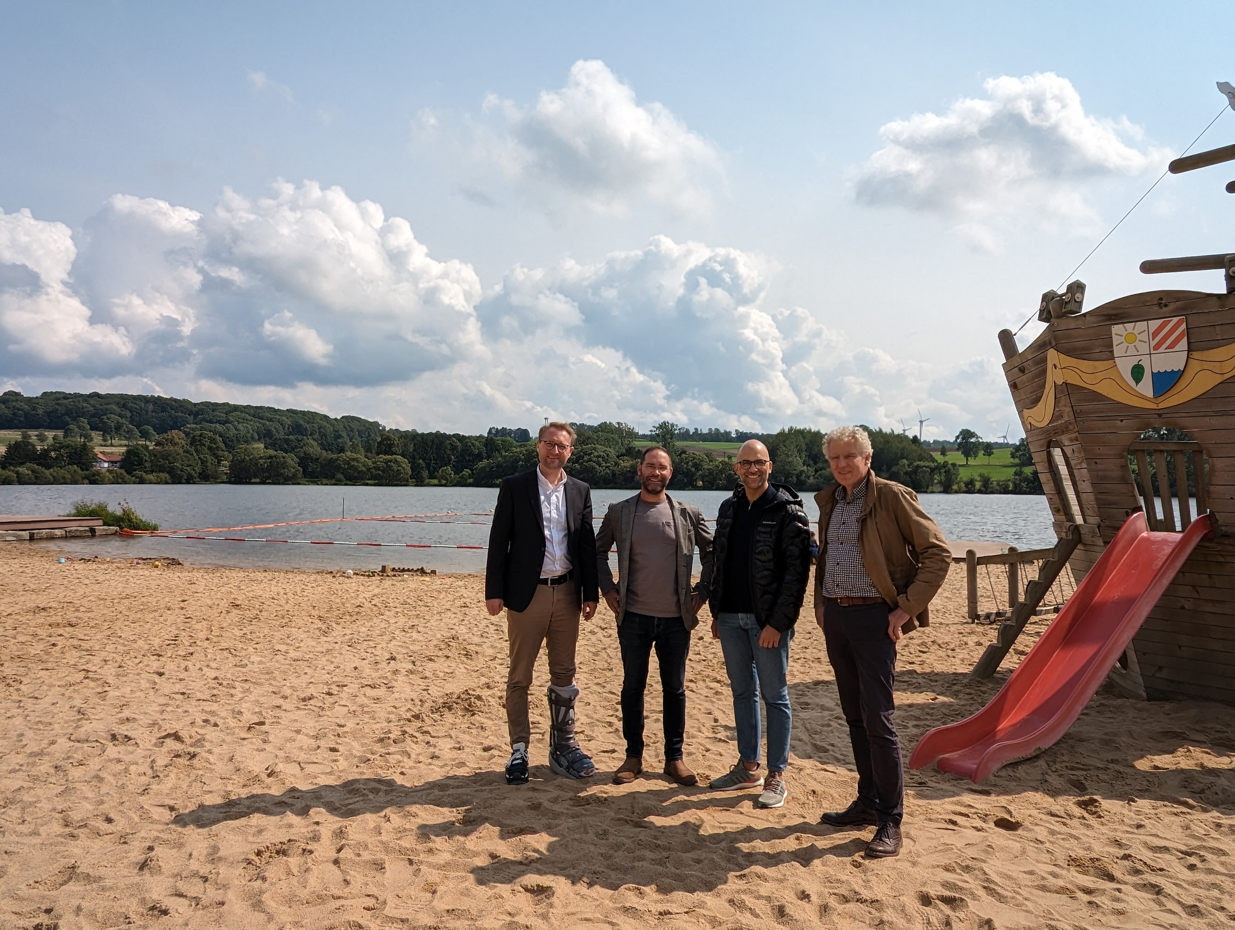 Der Erste Kreisbeigeordnete Dr. Jens Mischak (links), beim Besuch am Nieder-Mooser See. Dort trifft er gemeinsam mit Lorenz Kock (rechts), stellvertretender Leiter des Amts für Wirtschaft und den ländlichen Raum, unter anderem Daniel Heitzenröder (von rechts), Geschäftsführer der Camping Heitzenröder GmbH, und Florian Appel, Geschäftsführer der Erlebnis- und Freizeitwelt Nieder-Mooser See. 