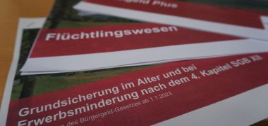 Eine Nahaufnahme von drei Papierstabeln. Wohngeld, Flüchtlingswesen und Grundsicherung im Alter ist darauf zu lesen.