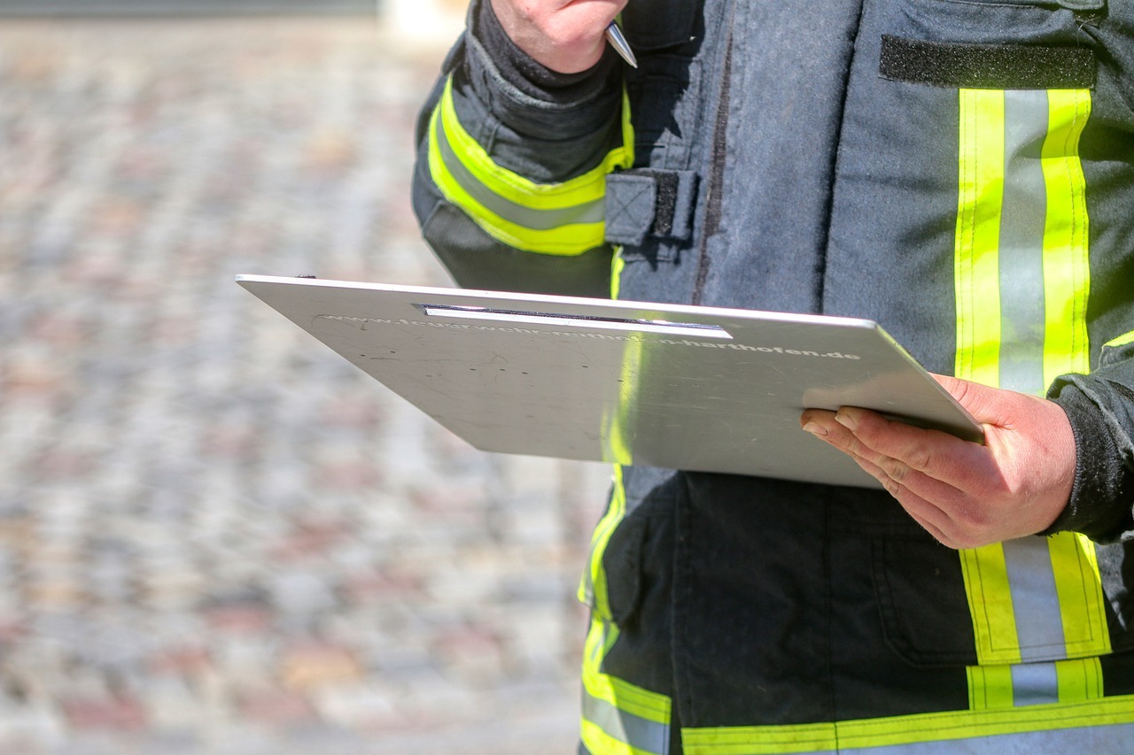 Ein Mensch mit Feuerwehrschutzkleidung hält ein Klemmbrett in der Hand. 