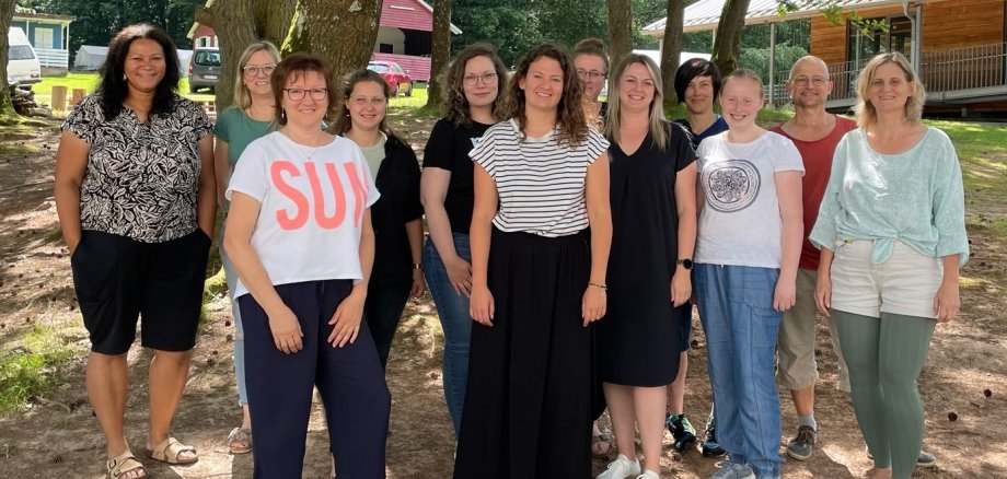 Zwölf Menschen haben sich im Kreisjugendheim in Landenhausen zum Gruppenbild aufgestellt. Sie stehen vor einer Baumgruppe.