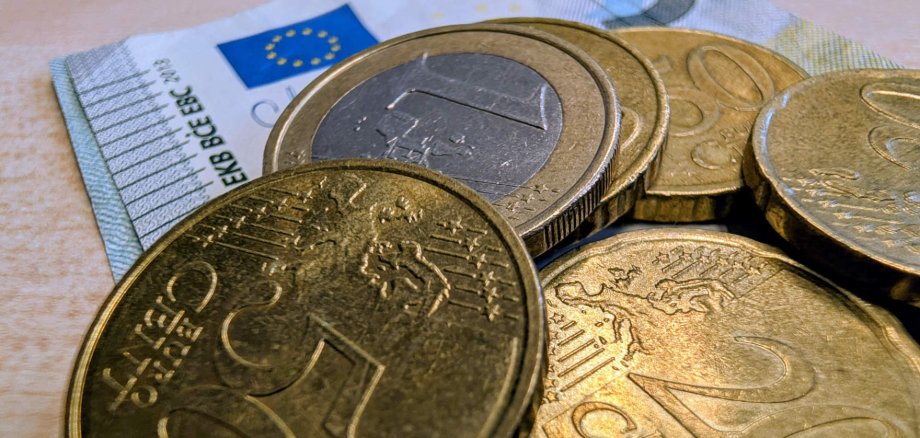 Nahaufnahme von Kleingelt. Darauf sind Euromünzen und ein 5-Euro-Schein zu sehen.