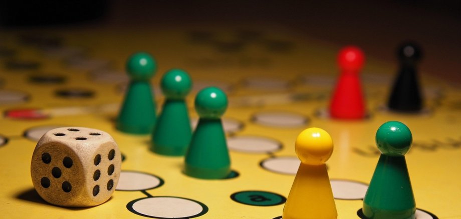 Ein Mensch-Ärgere-Dich-nicht-Spiel mit einigen bunten Spielfiguren und einem Würfel.