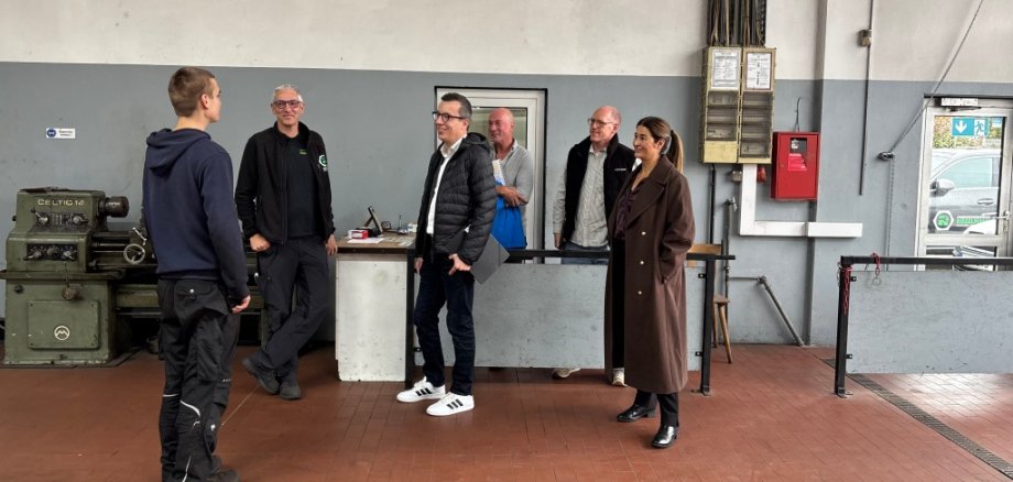 Jan (links) berichtet von seinem Arbeitsalltag beim Fahrzeugservice Riegelmann – Alsfelder Bremsendienst. Patrick Krug (dritter von links), Erster Kreisbeigeordneter sowie Schul- und Sozialdezernent, sowie Katja Diehl (von rechts), Vorstandsvorsitzende von Kompass Leben e.V., Lars Kersten, Lehrer an der Brüder-Grimm-Schule in Alsfeld, Michael Dippel, Werkstattleiter von Kompass Leben e.V., und Stefan Riegelmann, Inhaber vom Fahrzeugservice Riegelmann Alsfelder Bremsendienst, hören gespannt zu.