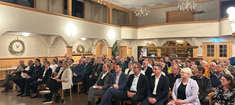 In einem Saal nehmen rund 90 Personen an einer Konferenz teil. 