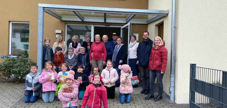 Abschlussbild vor dem Eingang: Senioren und Kinder haben sich gemeinsam für ein Gruppenbild aufgestellt und schauen in die Kamera.