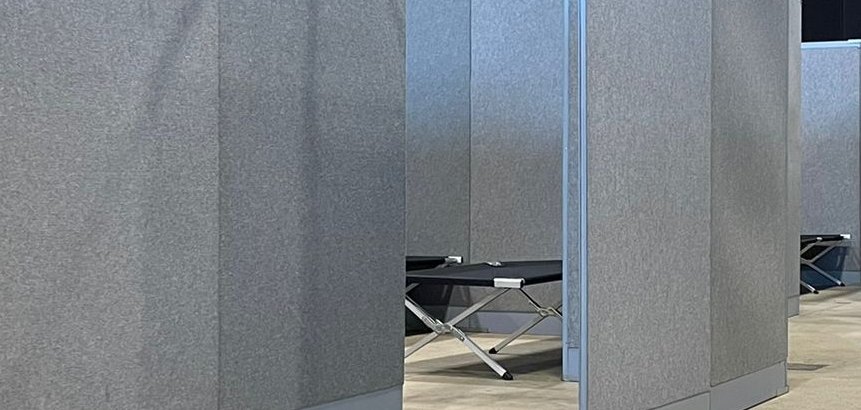 Zur Ankunft der ersten Flüchtlinge am Samstag ist die Notunterkunft in der Hessenhalle fertig hergerichtet. Zwischen den schwarzen Feldbetten wurden graue Trennwände aufgestellt, sodass separierte Räume für die Familien geschaffen werden konnten. 