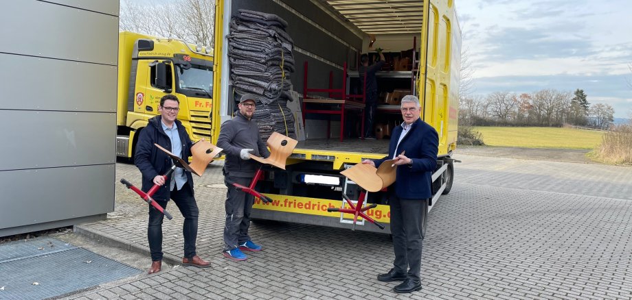 Landrat Manfred Görig (rechts) und Matthias Röse vom Amt für Schulische Bildung und Betreuung (links) freuen sich, dass der Vogelsbergkreis einen Beitrag zum Wiederaufbau der Schulen in der Ukraine leisten kann. Gabor Dallos von der Spedition Friedrich Friedrich (Mitte) liefert die Möbel zunächst nach Polen, von wo aus sie weiter in die Ukraine transportiert werden.    