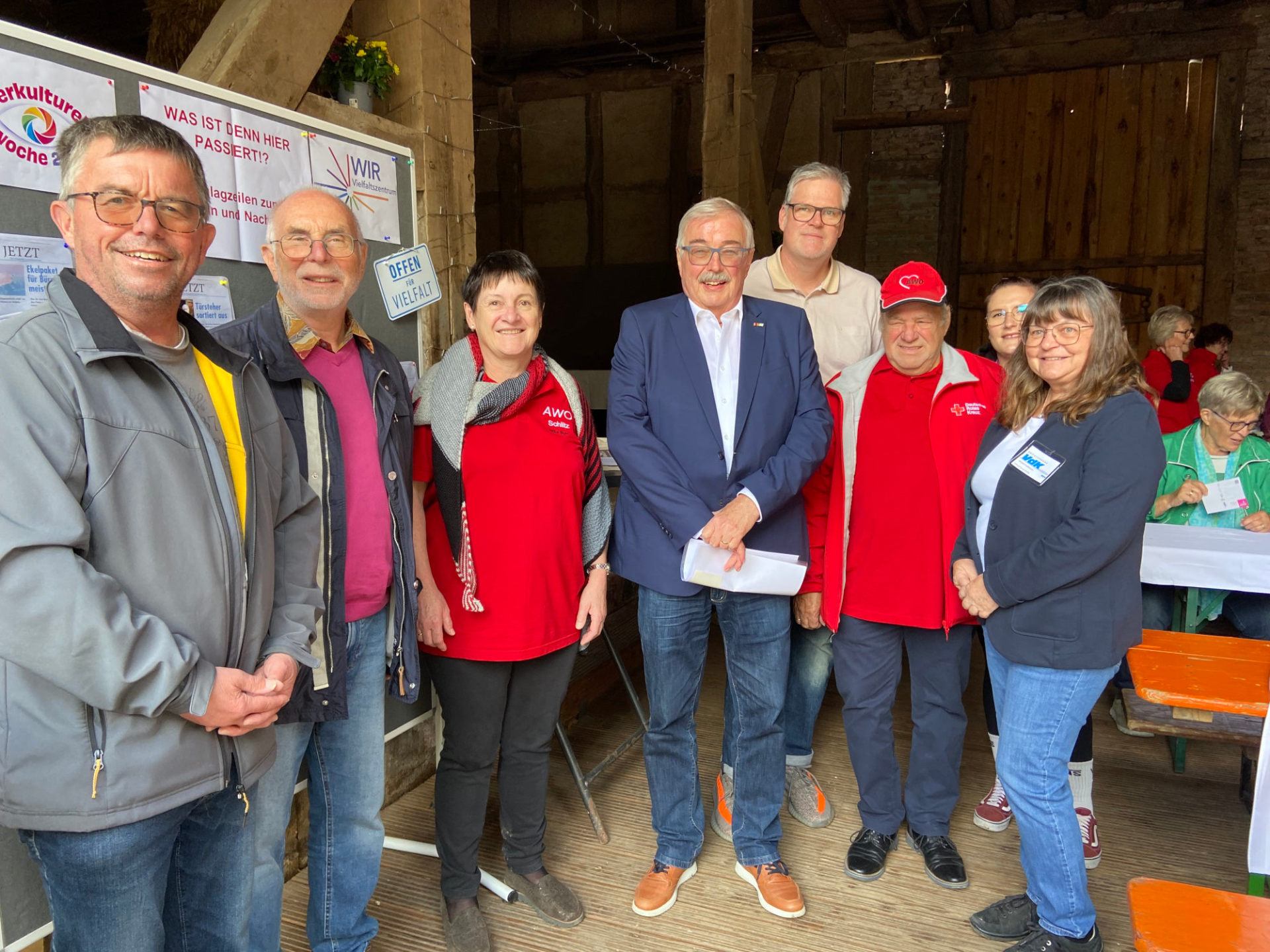 neun Menschen haben sich zu einem Gruppenbild aufgestellt und lächeln in die Kamera. 