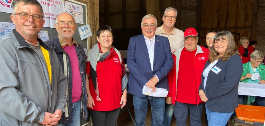 neun Menschen haben sich zu einem Gruppenbild aufgestellt und lächeln in die Kamera. 