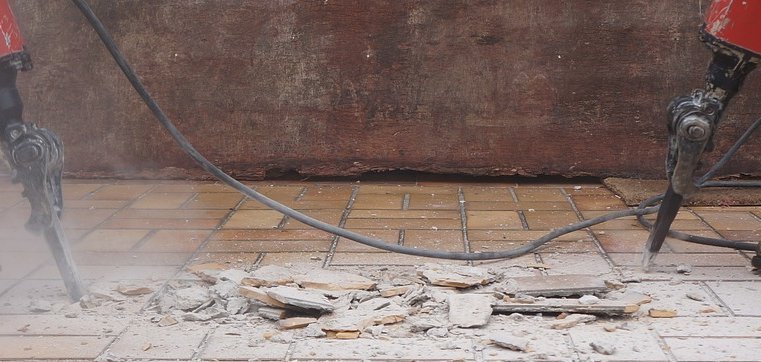 Zwei Menschen mit Presslufthammer stemmen den Fliesen vom Boden