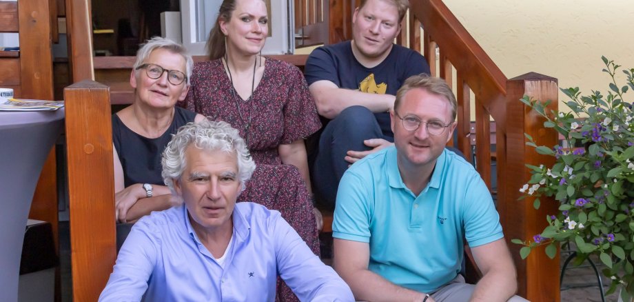 (hinten v. l). Gudrun Stumpf, Elisabeth Eisenbarth, Sebastian Heil, (vorne v. l.) Lorenz Kock (Projektleitung im Amt für Wirtschaft und den ländlichen Raum) sowie Jurymitglied Dr. Jens Mischak haben weitere Vogelsberg ORIGINAL-Produkte ausgezeichnet. Sie sitzen auf einer Holztreppe und schauen in die Kamera