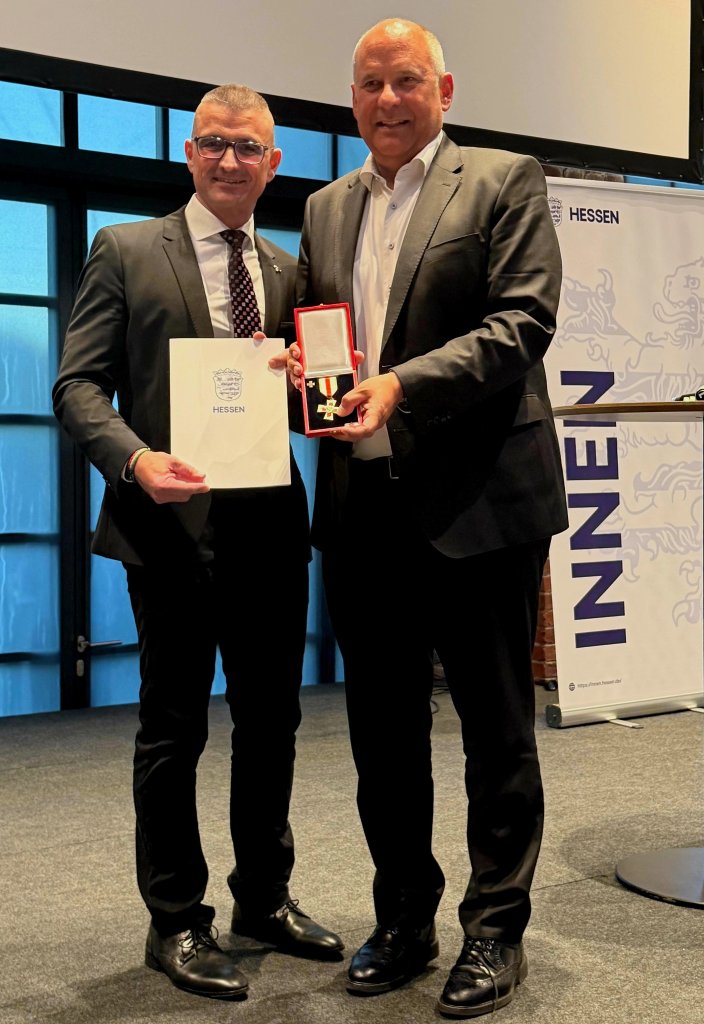 Kreisbrandinspektor Marcell Büttner und Innenminister Roman Poseck lächeln in die Kamera.