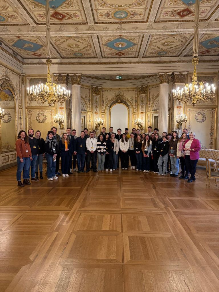 Gruppenbild im hessischen  Landtag -- unter einer reich verzierten Decke haben sich rund 20 Menschen in einem Saal aufgestellt und schauen in die Kamera