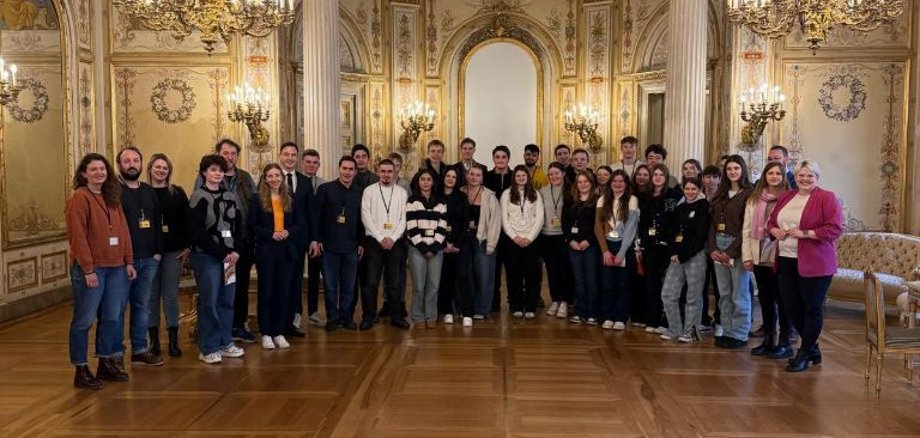 Gruppenbild im hessischen  Landtag -- unter einer reich verzierten Decke haben sich rund 20 Menschen in einem Saal aufgestellt und schauen in die Kamera